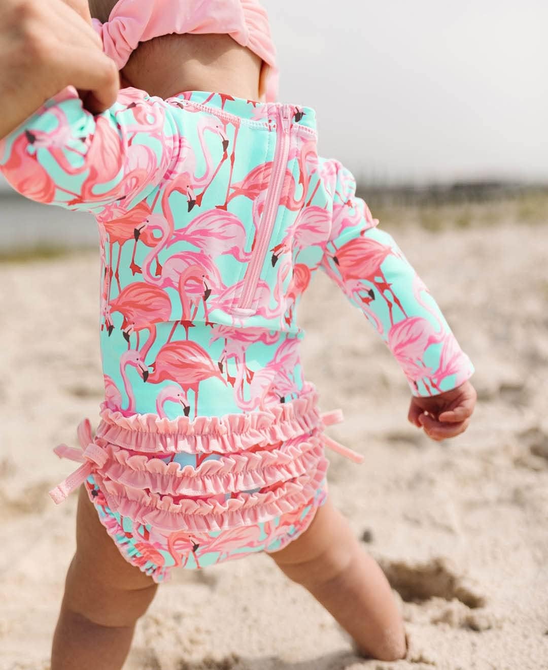 RuffleButts Baby Girls UPF 50+ Sun Protection Novelty Print Long Sleeve One Piece Rash Guard Swimsuit with Zipper