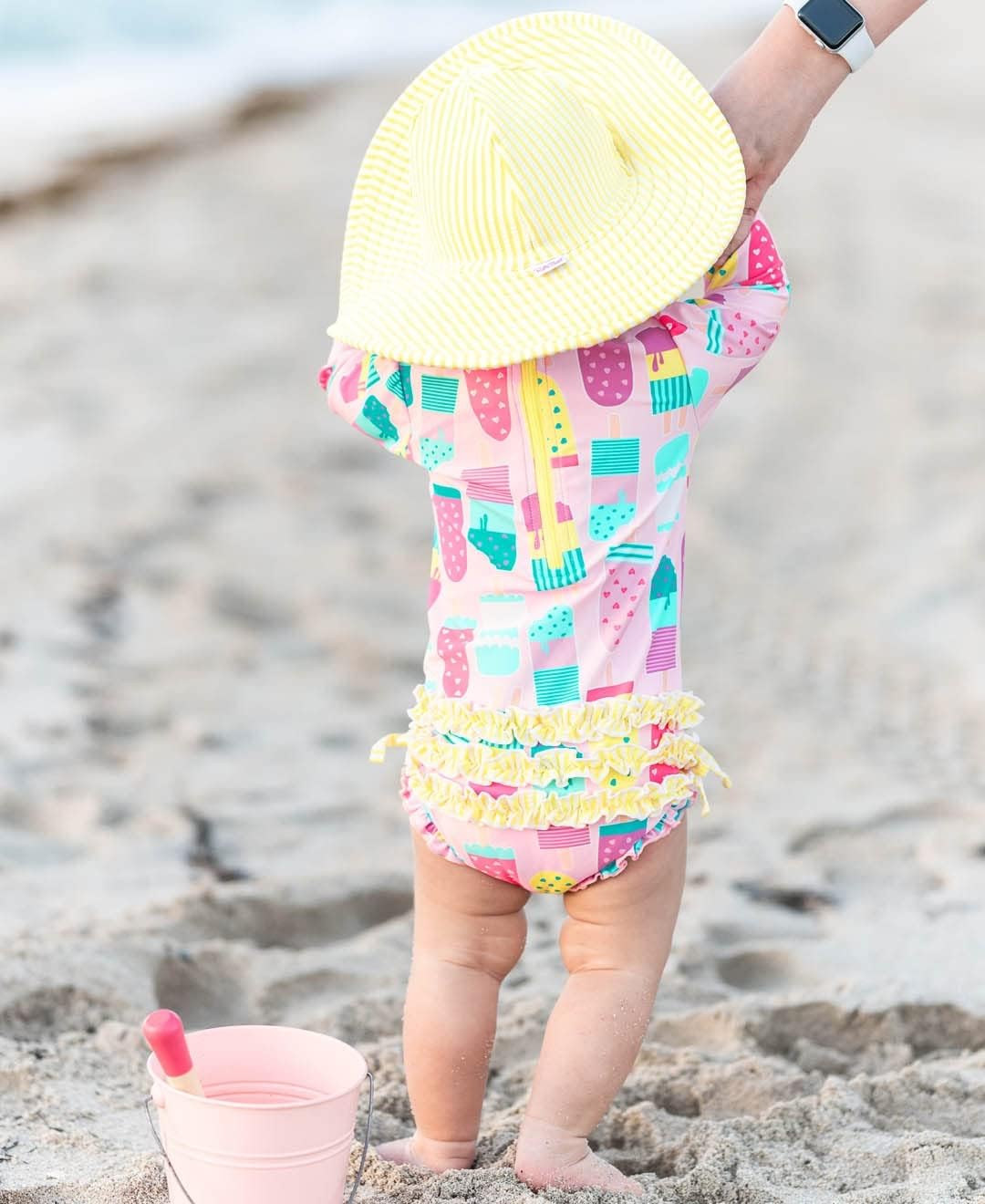 RuffleButts Baby Girls UPF 50+ Sun Protection Novelty Print Long Sleeve One Piece Rash Guard Swimsuit with Zipper