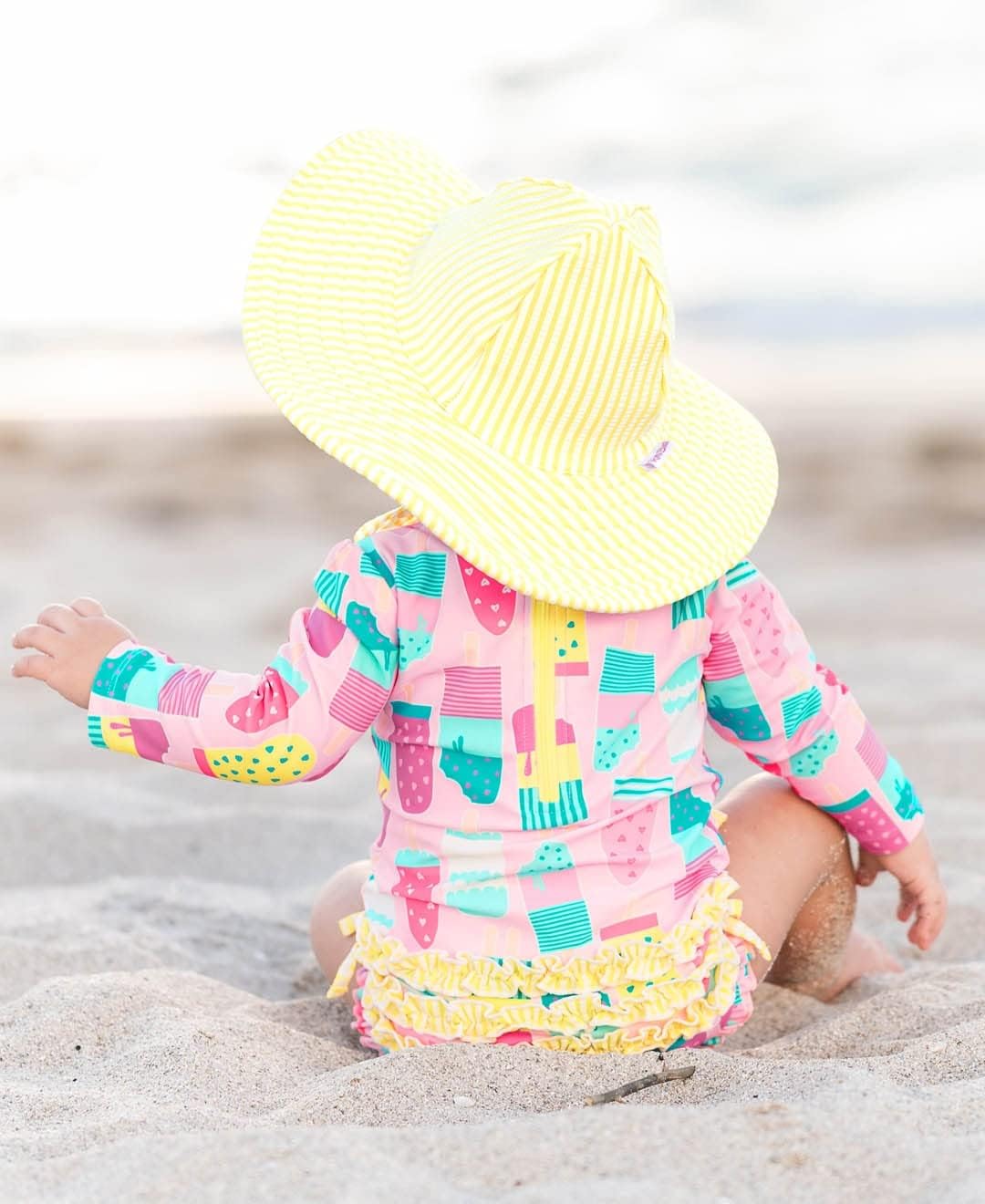 RuffleButts Baby Girls UPF 50+ Sun Protection Novelty Print Long Sleeve One Piece Rash Guard Swimsuit with Zipper
